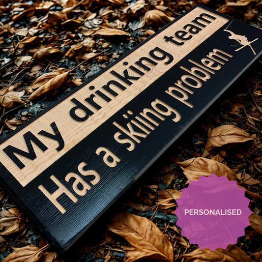 Personalised wooden ski trail sign reading 'My drinking team has a skiing problem' on autumn leaves
