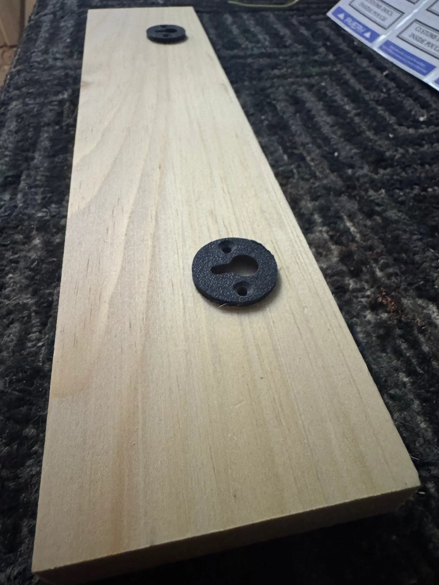 Unfinished wooden sign with two keyhole mounting brackets on a textured surface