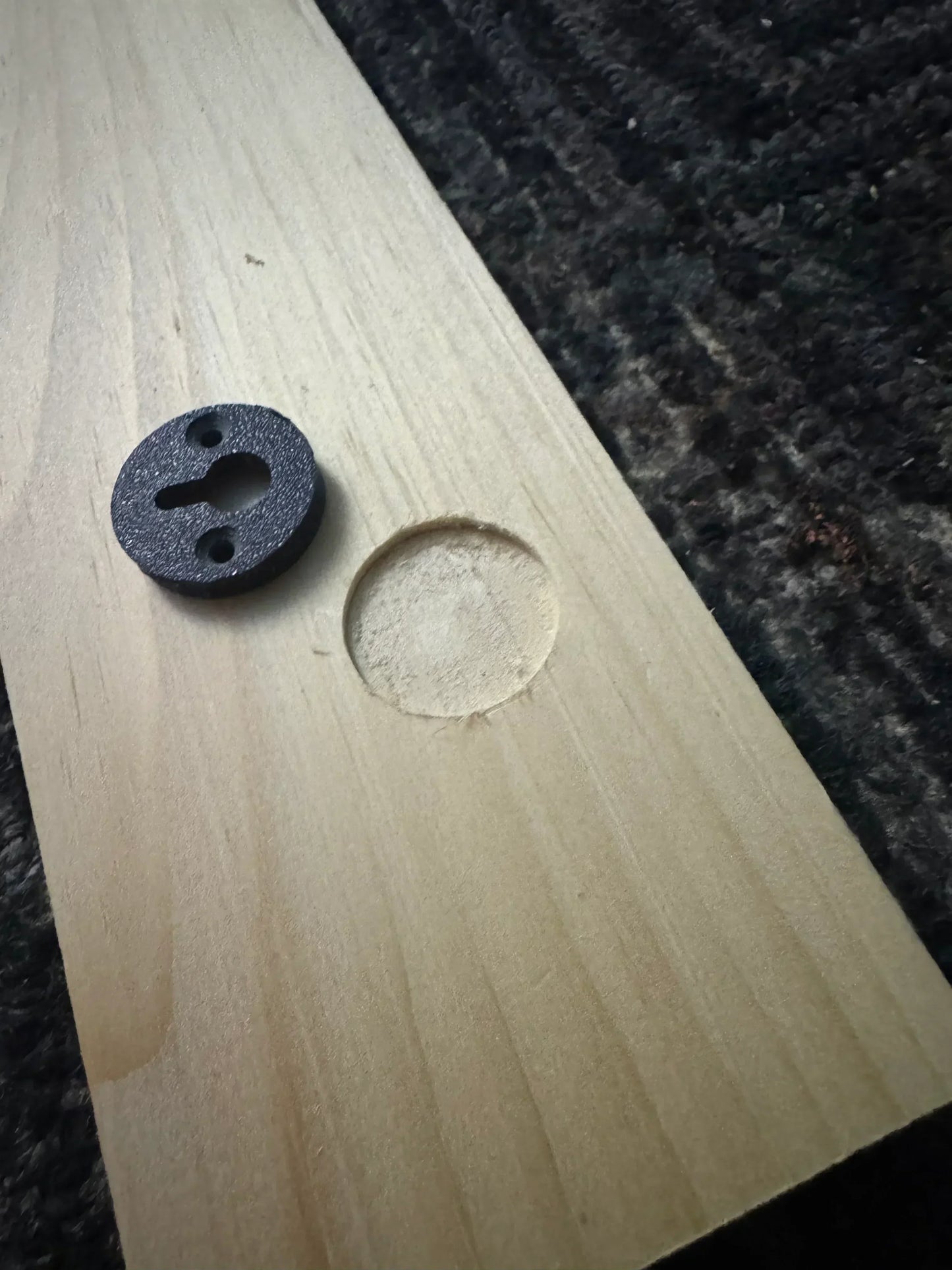 Close-up of a wooden sign with a round mounting bracket and recessed hole for hanging hardware