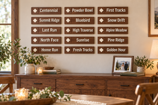Fifteen small walnut-toned ski wedding table signs arranged in three columns and five rows above a sideboard at home; illustrative 3 by 13 inch sign display