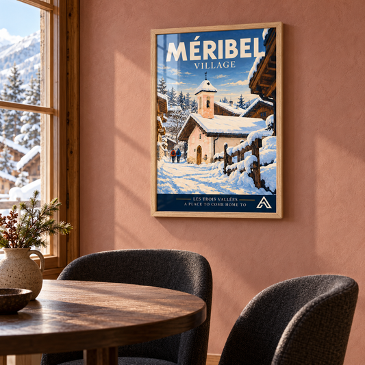 Méribel Village art print in Natural Oak on a dusty-rose wall beside a dining table and charcoal chairs, with winter sunlight reflecting across the glazing.