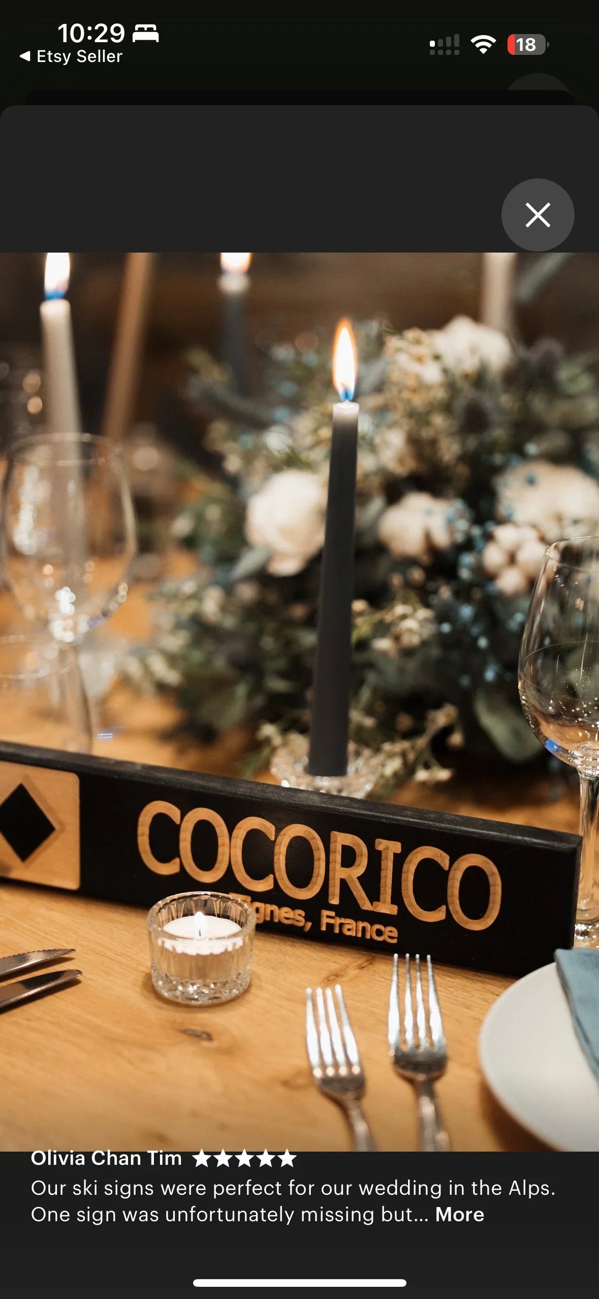 Rustic wood ski trail table sign for wedding, surrounded by candles, flowers, and glassware