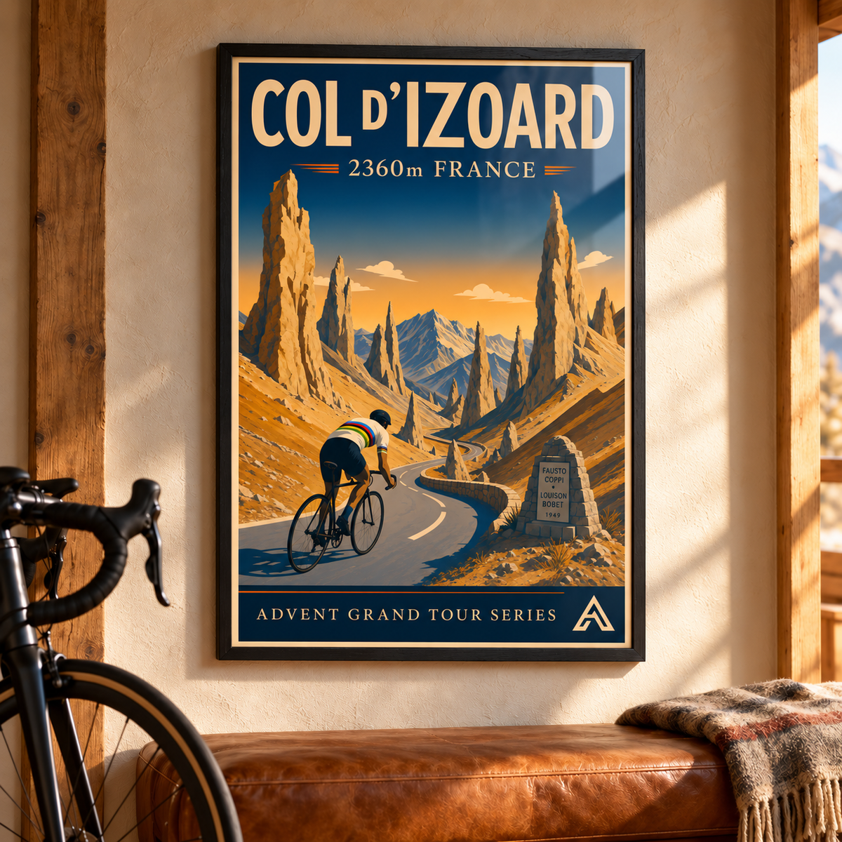 Col d’Izoard art print in a Black Ash frame above a leather bench beside a road bicycle, showing a cyclist in a white world champion jersey among golden Alpine rock spires.