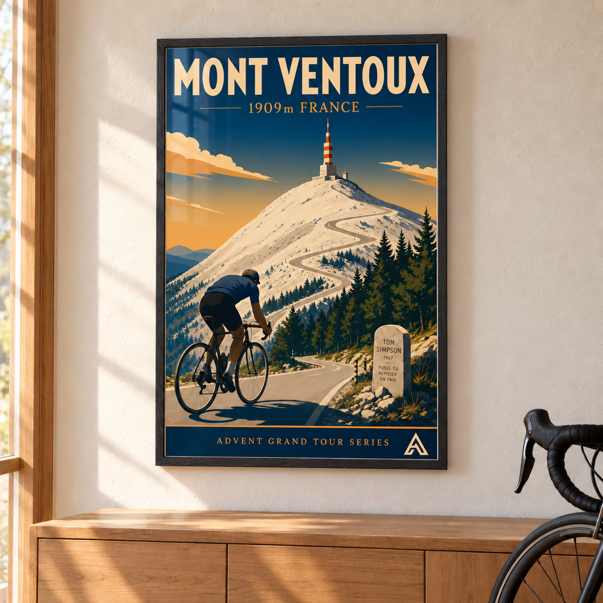 Mont Ventoux art print in a slim Black Ash frame above an oak cabinet beside a road bicycle, showing a cyclist climbing toward the summit tower and the Tom Simpson memorial.
