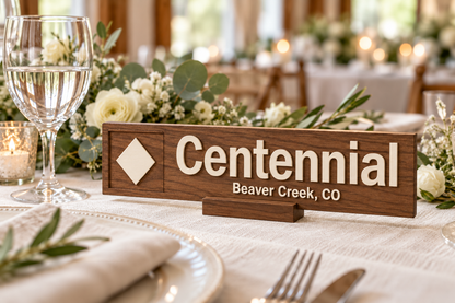 Walnut-toned stain with ivory lettering and accents on a personalised ski wedding table marker; illustrative finish mockup