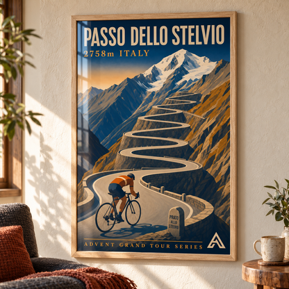 Passo dello Stelvio art print in a Natural Oak frame above a charcoal sofa in a sunlit mountain home, showing a cyclist beneath stacked mountain switchbacks.