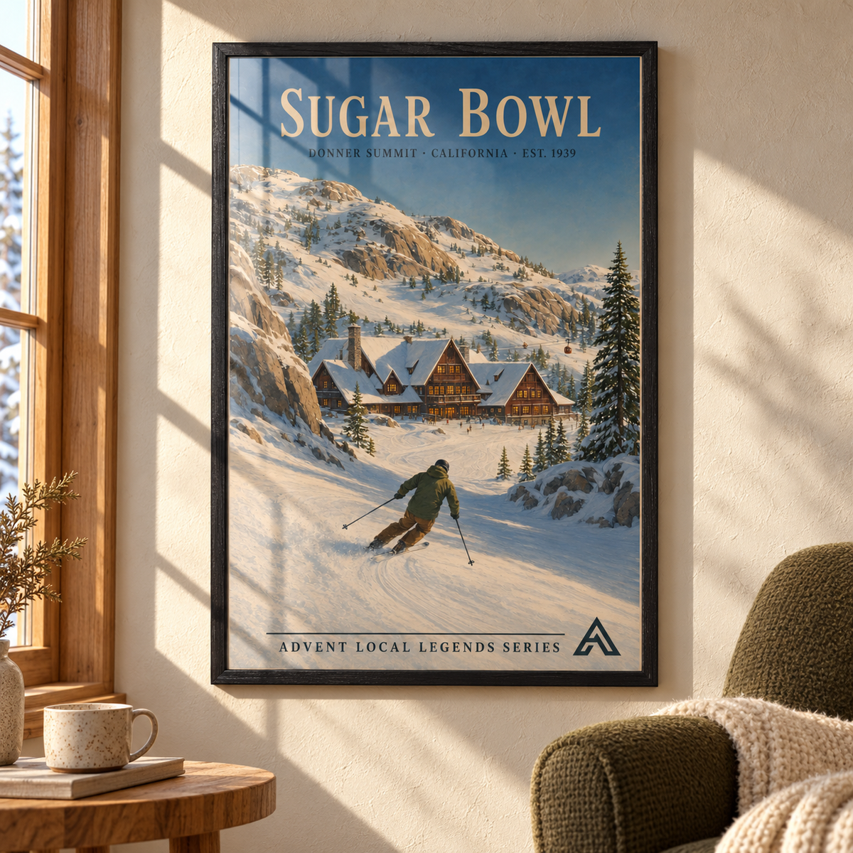 Sugar Bowl art print in a Black Ash frame on a sunlit wall beside an olive armchair, with window reflections across the snowy mountains, alpine lodge and skier artwork.